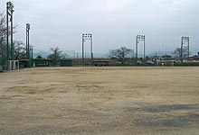 広々とした野球場の周囲にダッグアウトやナイター照明が設置されている町営球技場の写真
