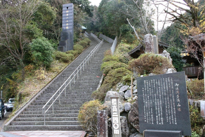 右側に説明書きが彫刻された石と標高240メートルと書かれた板がある釈迦院御坂遊歩道を正面から写した写真