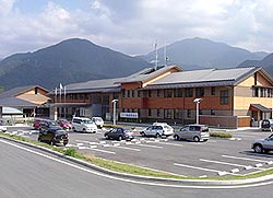 数台の車が停まっている駐車場と2階建てで三角屋根の美里町役場砥用庁舎の写真